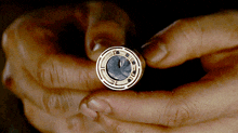a close up of a person holding a coin with a circular design on it