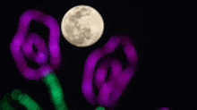 a full moon is rising over a bunch of purple and green lights .