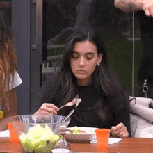 a woman is sitting at a table eating food with a fork .