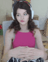 a woman wearing headphones and a pink top sitting in a chair