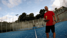 a man in a red shirt is holding a tennis racket