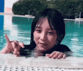 a woman is swimming in a pool and making a funny face