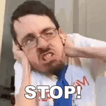 a man wearing glasses and a blue tie is making a funny face and saying stop .