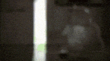 a blurred image of a person standing in a dark room with a light behind them .