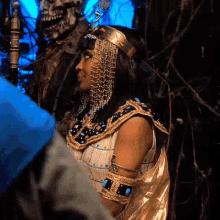 a woman in a costume of a pharaoh is standing in front of a skeleton .