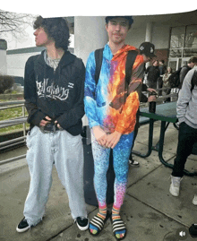 a man wearing a black billabong sweatshirt stands next to another man