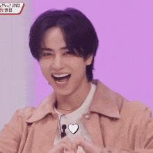 a man making a heart shape with his hands with a purple background