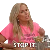 a woman sitting at a table with a pink shirt that says stop it