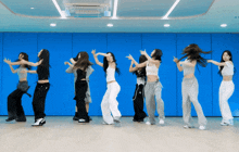 a group of young women are dancing in a room with a blue wall