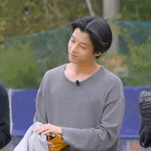 a young man wearing a gray sweater is holding a baseball glove