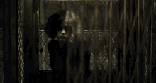 a woman is behind a chain link fence looking out
