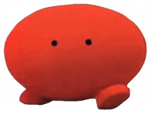 a red stuffed animal with two black holes in it 's eyes is sitting on a white surface .