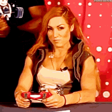 a woman is sitting at a table holding a game controller .