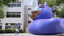a man in a blue costume is standing in front of a giant blue rubber duck
