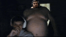 a man wearing headphones is looking at a very large belly of a man .