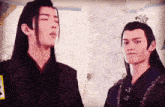 two asian men with long hair are standing next to each other