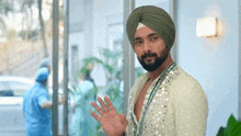 a man wearing a turban and a white shirt waves his hand