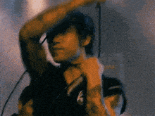 a man is singing into a microphone while wearing a shirt with the letter k on it