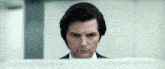a man in a suit and tie looks at the camera