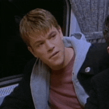 a man wearing a red shirt and a black jacket is looking at something
