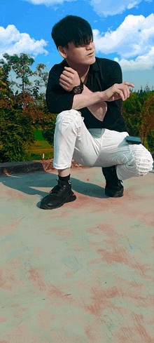 a young man in a black shirt and white pants is squatting down