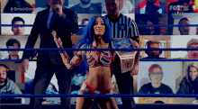 a woman with blue hair is standing in a wrestling ring holding a championship belt