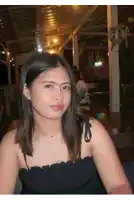 a woman in a black dress is sitting at a table in front of a bar