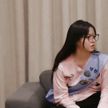 a woman wearing glasses is sitting on a couch .