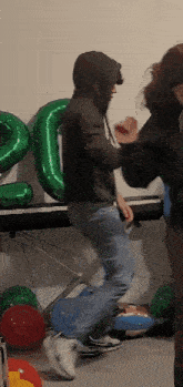 a man in a hoodie is jumping in front of a piano and balloons that have the number 20 on them