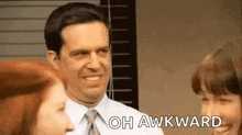 a man in a suit and tie is smiling and talking to a woman in an office .