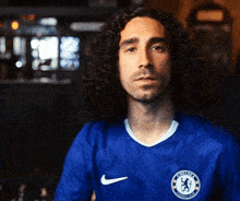 a man with curly hair is wearing a blue chelsea jersey