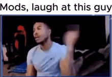 a man in a white shirt is laughing while sitting in front of a computer screen .