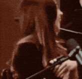 a woman singing into a microphone while playing a flute