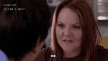 a woman with red hair is talking to a man in a kitchen and says `` ok '' .