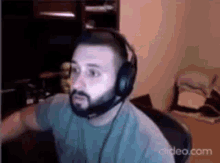 a man with a beard is wearing headphones and a microphone while sitting at a desk .