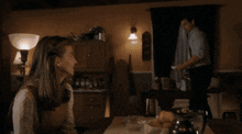 a man and a girl are sitting at a table with a lamp in the background