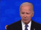 a man in a suit and tie stands in front of a blue background that says cnn