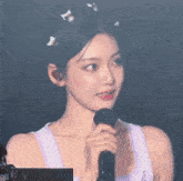 a woman in a purple tank top is holding a microphone and smiling .