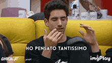 a man is sitting on a yellow couch with the words ho pensato tantissimo written on the bottom