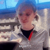 a woman in a striped shirt is standing in front of a computer and says huh ?
