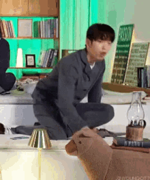 a man in a suit is kneeling down in a living room next to a stuffed animal .