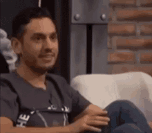 a man is sitting on a couch with his legs crossed and looking at the camera .