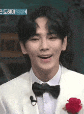 a man in a tuxedo with a bow tie and a red rose on his lapel