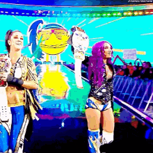 two women with purple hair are standing next to each other on a stage holding trophies .