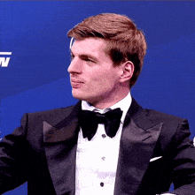 a man in a tuxedo with a bow tie looks to his right
