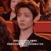 a man sits in a theatre with chinese writing on the screen