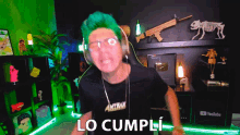 a man with green hair is wearing headphones and a necklace that says antmax
