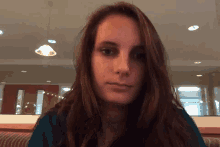 a woman with long brown hair looks at the camera with a serious look on her face