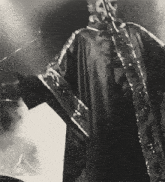 a black and white photo of a man in a robe holding a microphone