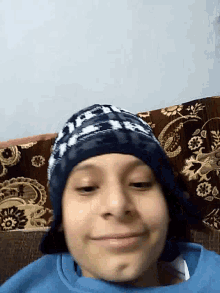 a young boy wearing a blue sweater and a blue hat